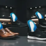 Work shoes, sneakers, and boots with cushioned insoles displayed in a dark-themed Footinst store, highlighting comfort for all-day standing.